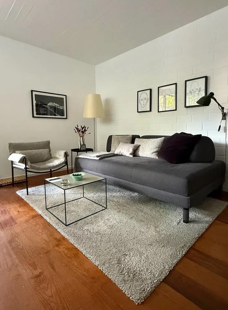 Wohnraum mit Schlafsofa, Sessel und Bilderwand